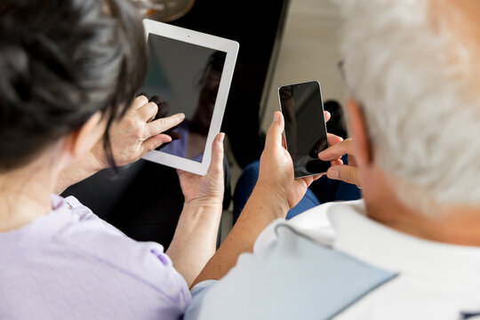 Senior couple using smartphone and tablet with blank screens - Powered by Adobe