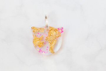 Clear Resin Cat Head Tag with Gold Foil and Pink Glitter on White Marble Background