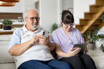 Senior couple using smartphone and tablet at home