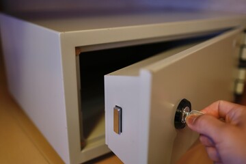 手に鍵を持ち小型金庫を施錠または解錠するイメージ