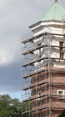 Rusztowanie wielopoziomowe przy białej wieży z cegły © tomo81