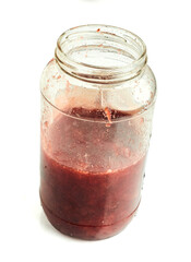 Half filled strawberry jam jar with visible fruit pieces  isolated on white background
