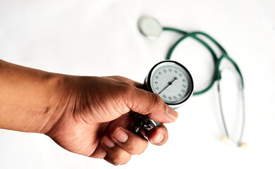 Hand holding a blood pressure gauge with stethoscope in background isolated on white background
