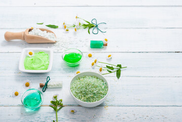 beauty product samples with chamomile flowers on white wooden table