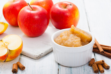apple jam at porcelain dish, apples, cinnamon, white wood table background