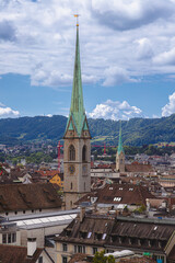 Church tower with green spire overlooking Zurich cityscape