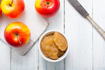 apple jam at porcelain dish, apples, cinnamon, white wood table background