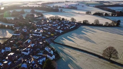 Aerial drone footage capturing upward moving perspective of sun illuminated undulating terrain in northern English region during the colder season.