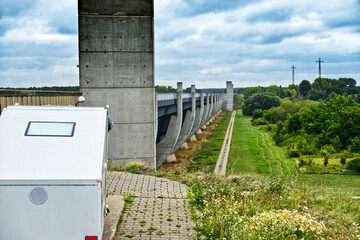 Camper van parked beside magdeburg water bridge, highlighting architectural engineering spanning waterway against scenic german landscape