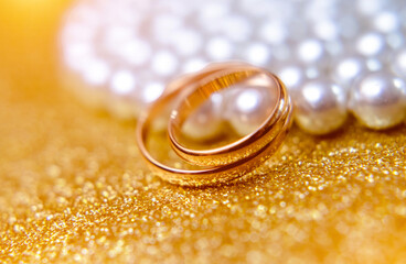 Gold wedding rings lie on a pearl necklace
