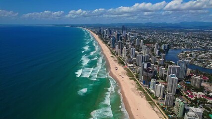 Breathtaking aerial footage of Gold Coast showcasing coastal skyscrapers, endless sandy beaches, ocean waves, and blue skies. Vibrant summer day highlights this luxurious resort city.