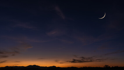 Crescent moon on dusk sky background, Twilight sky clouds over landscape mountain in summer evening, Religion of Islamic and free space text Ramadan Kareem, Eid Al Fitr, Eid Al Adha, Eid Mubarak