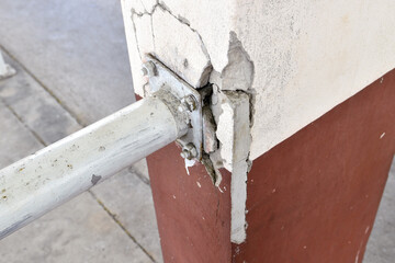 concrete pillar is cracked in area where metal railing attached