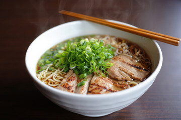 A steaming bowl of delicious japanese ramen noodles with sliced pork and green onions, a savory meal