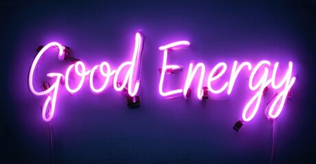 Bright purple neon sign displays Good Energy. Wall background is dark blue. Simple, modern aesthetic. Positive message, vibrant illumination.