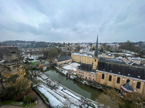 View of the Alzette River and Neum&uuml;nster Abbey in the Grund on a winter day with snow and cloudy skies. Luxembourg