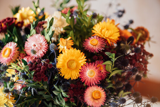 Autumn bouquet with vibrant strawflowers and mixed foliage in warm seasonal colors