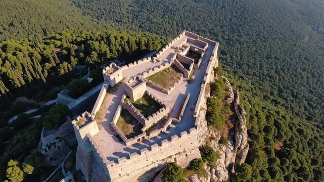 Aerial view of the Acrocorinth fortress and ancient ruins on rocky hill surrounded by lush green landscape
