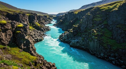 Obraz premium Majestic Turquoise River Carving Through Rugged Icelandic Canyon Under Clear Blue Sky