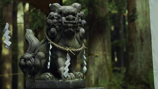 神社の境内にたたずむ狛犬像。森の中に佇む日本の伝統文化の象徴