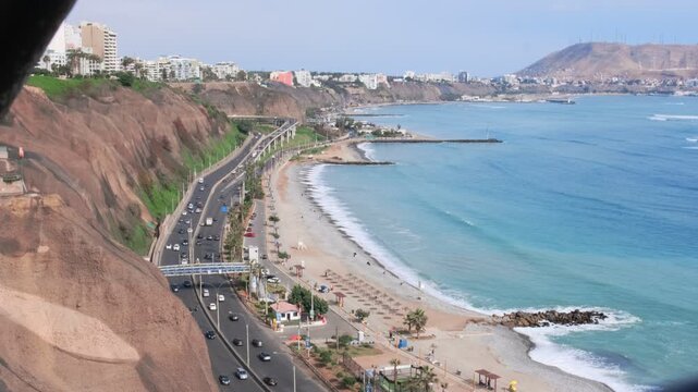 Paraglider flying over the miraflores district coastline, lima, peru, with the morro solar in the background