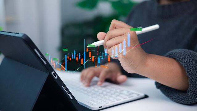 Person analyzing financial growth and stock market data on digital tablet with stylus and holographic candlestick chart for modern investment and business strategy concept