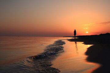 Fototapeta premium breathtaking sunrise silhouette of person standing on shore essence of summer dawn
