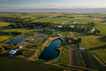 Aerial view of sustainable farm with green crops, water bodies, and farm structures, showcasing agricultural diversity and eco friendly practices in rural landscape