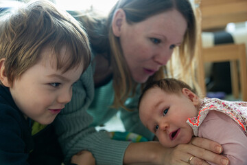 Mama und Bruder spielen mit Baby