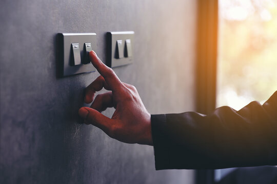The young man's hand turned off the light switch. Energy saving concept. Hand Turning Off Light Switch. Saving Electricity with a Single Action.