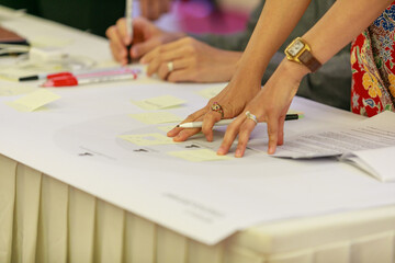 Collaborative Brainstorming Session: Colleagues Pointing and Discussing Ideas on Sticky Notes