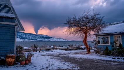 Winter sunset over a lake, with a dramatic sky and snow-covered landscape