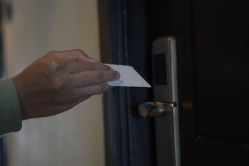 A woman will attach a hotel room key card to open the door. The one cropped on her hand