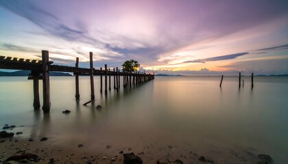 Fototapeta premium Serene sunset over a decaying wooden pier extending into calm sea