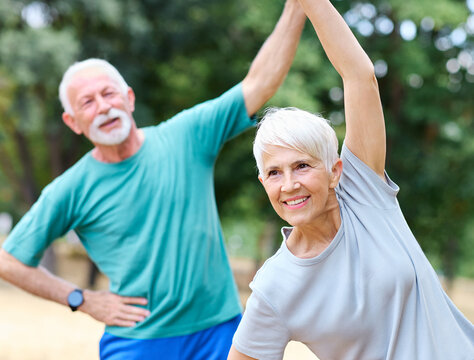 Portrait os a happy beautiful elderly senior mature couple exercising and stretching outdoors