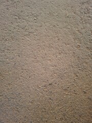 Close-up view of a rough brown surface texture, resembling concrete, asphalt, or compacted earth. This high-resolution background is perfect for design, construction themes, or industrial