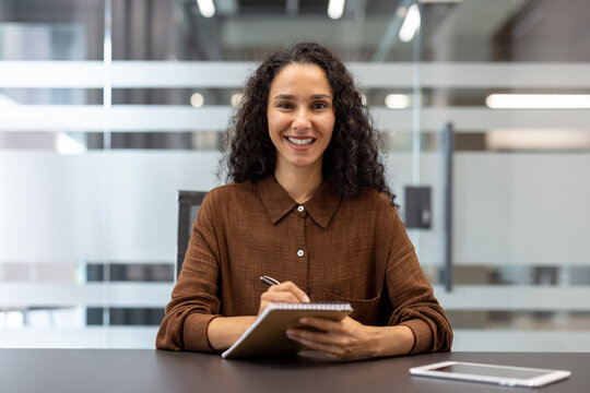 Confident professional woman taking notes during a meeting at a modern office