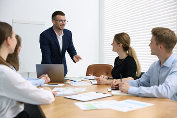 Business coach giving presentation to group of people in office