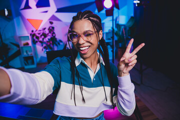 Charming African American female vlogger recording video in a neon-lit studio showcasing vibrant atmosphere and casual style