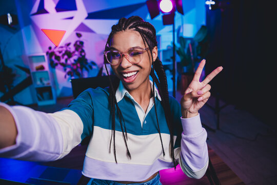 Charming African American female vlogger recording video in a neon-lit studio showcasing vibrant atmosphere and casual style - Powered by Adobe