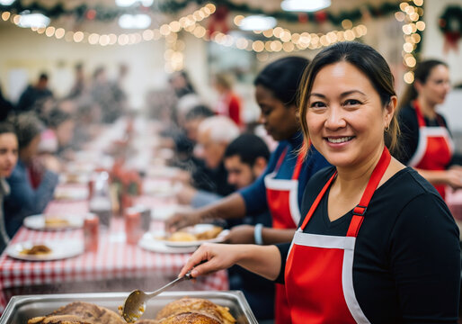 A smiling female volunteer looks directly at the camera while serving a hot holiday meal from a large tray at a bustling community event.