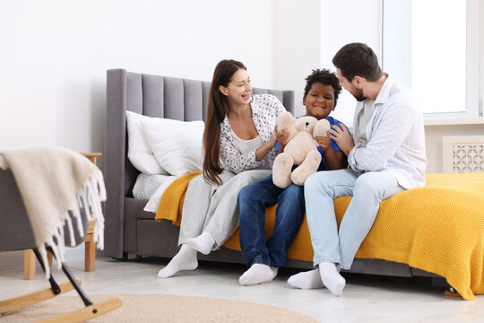 Adoption. Happy parents and their son on bed at home