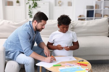 Obraz premium Adoption. Father and his son drawing together at table indoors
