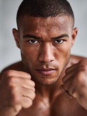 Fototapeta premium A focused male boxer with a serious expression, showing determination and strength. Ideal for sports and fitness themes.