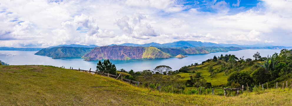 Panoramic view of Lake Toba from Sibea-bea Hill in Samosir, North Sumatra, Indonesia. The breathtaking landscape features the vast volcanic lake surrounded by lush green hills and mountains, showcasin