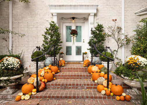 Fall, autumn in beautiful American suburban brick home with stairway entrance, leaves, and variety of pumpkins and gourds arranged artfully as decoration