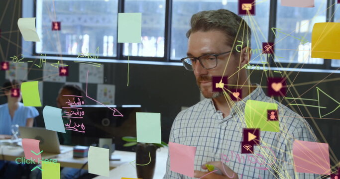 Checkered-shirted man writing on glass partition in office, with sticky notes and icons, copy space - Powered by Adobe