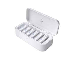 White charging case with earbuds.  Five earbuds nestled in charging slots, lit. Lid open.  Compact, modern design