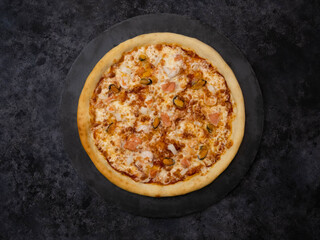 Enjoy a delicious pizza topped with gooey cheese, seafood products, zesty sauce, and a variety of mouthwatering toppings on black background.