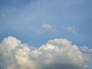 Bright fluffy white clouds floating across a clear blue sky on a sunny afternoon